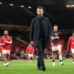 Michael Carrick caminha cabisbaixo à frente dos jogadores do Manchester United em Old Trafford, sinal de pressão sobre o comando técnico na Premier League 2026/27