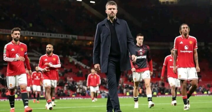 Michael Carrick caminha cabisbaixo à frente dos jogadores do Manchester United em Old Trafford, sinal de pressão sobre o comando técnico na Premier League 2026/27