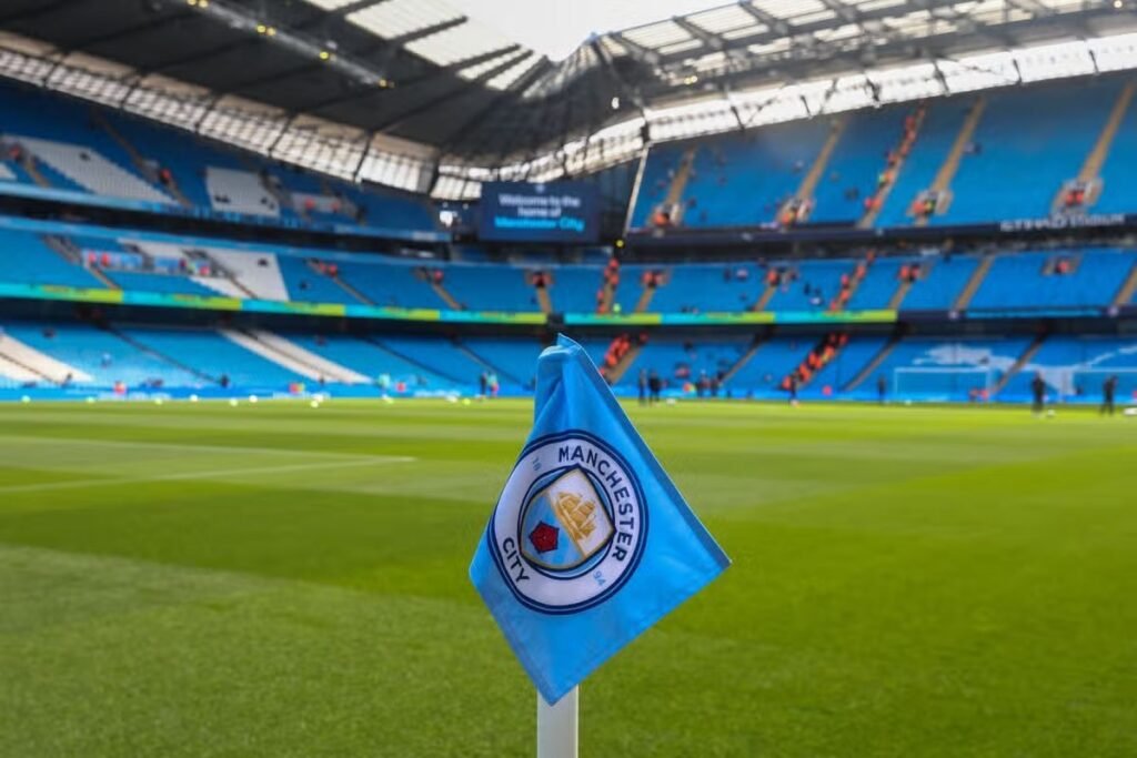 Bandeirinha de escanteio com o escudo do Manchester City no gramado do Etihad Stadium