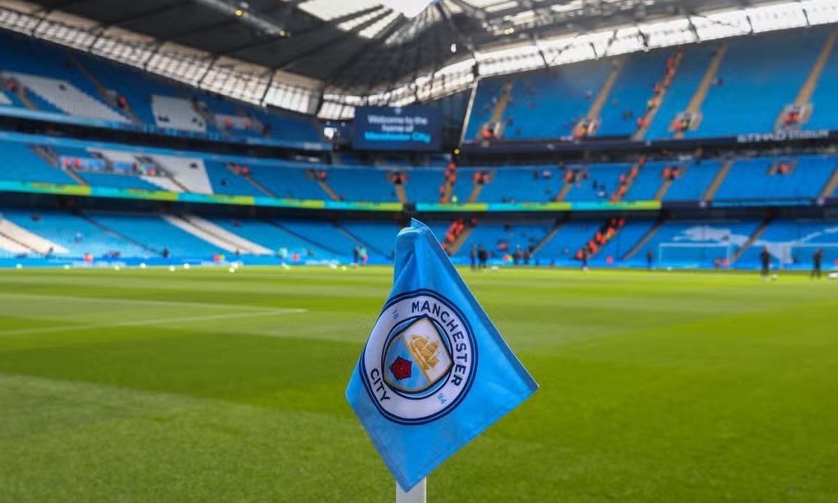 Bandeirinha de escanteio com o escudo do Manchester City no gramado do Etihad Stadium