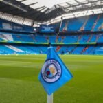 Bandeirinha de escanteio com o escudo do Manchester City no gramado do Etihad Stadium